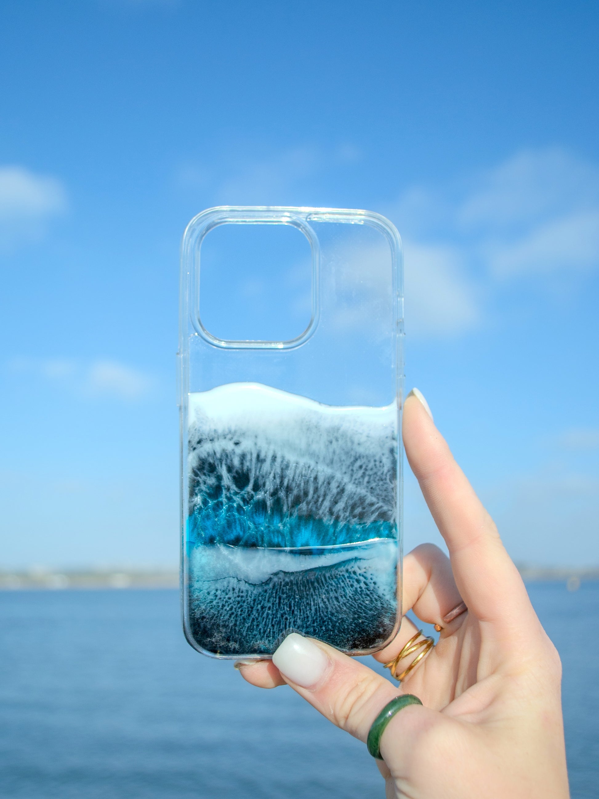 See-through iPhone case with black and blue resin ocean waves.