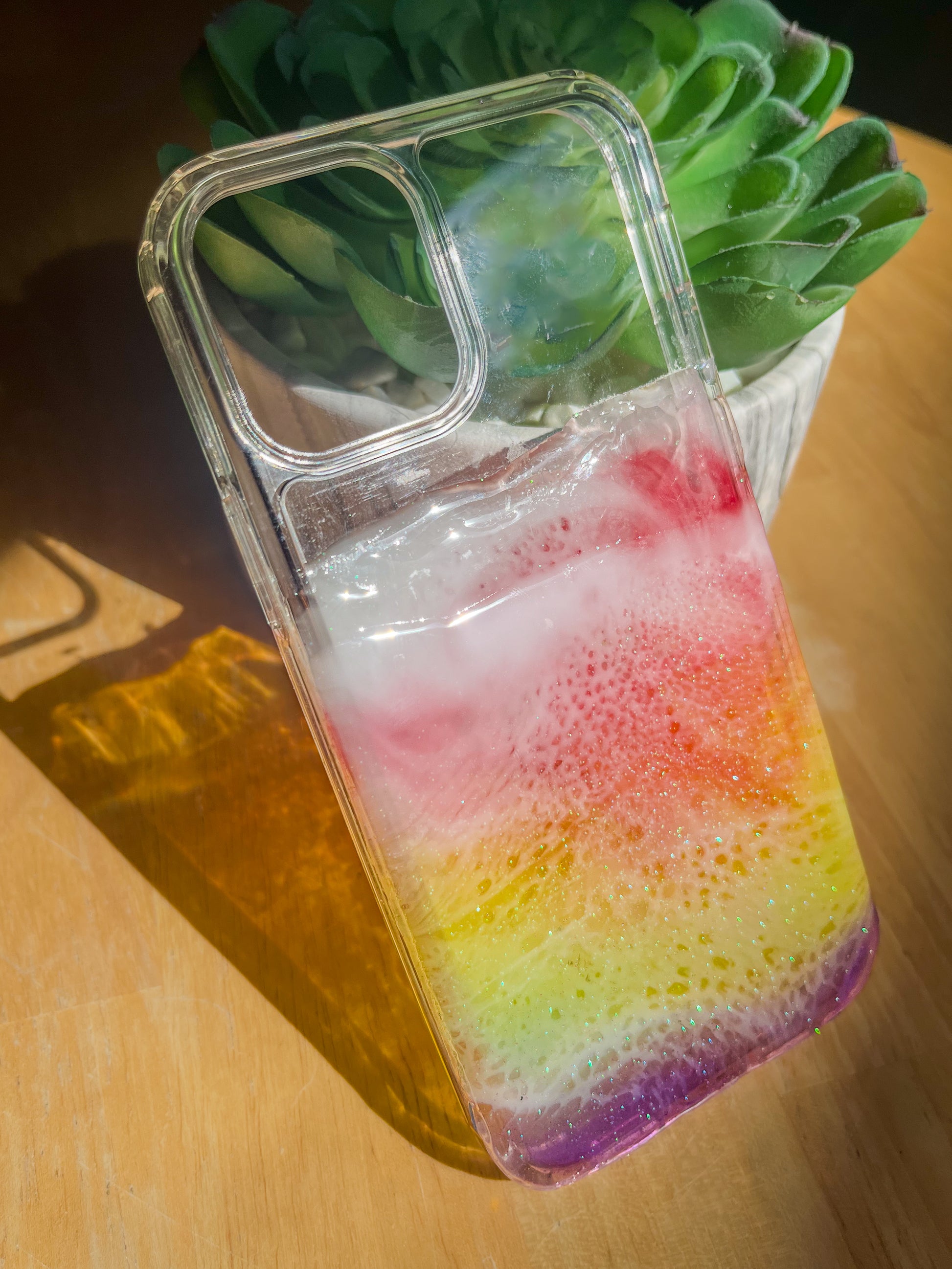 See-through rainbow resin ocean phone case casting colorful shadow.