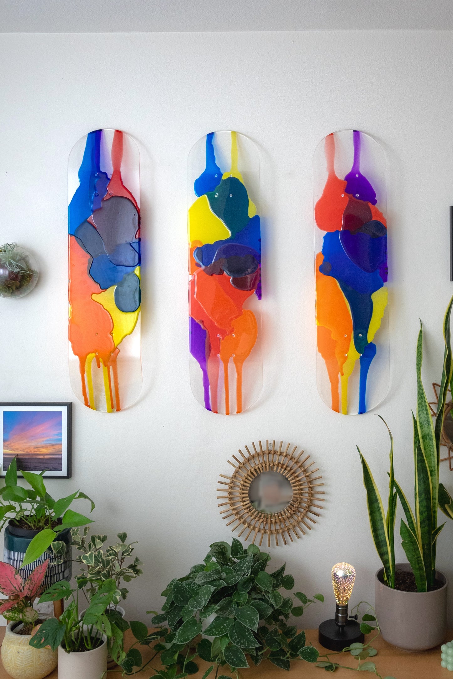Three piece see-through stained glass skateboard deck wall art with red, orange, yellow, blue and purple resin layers.