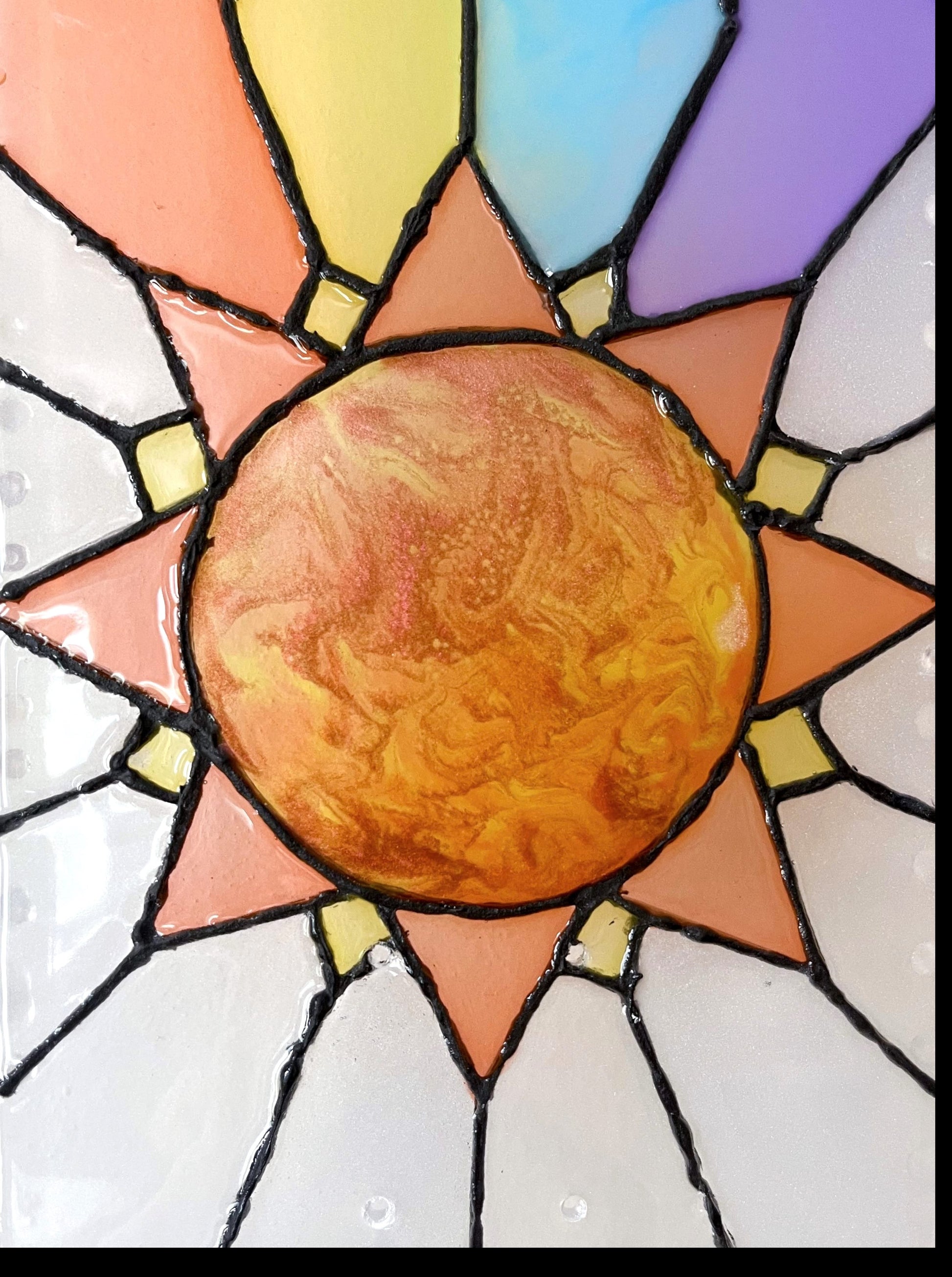 Close up of iridescent orange, yellow and red resin sun on see-through stained glass skateboard deck wall art.