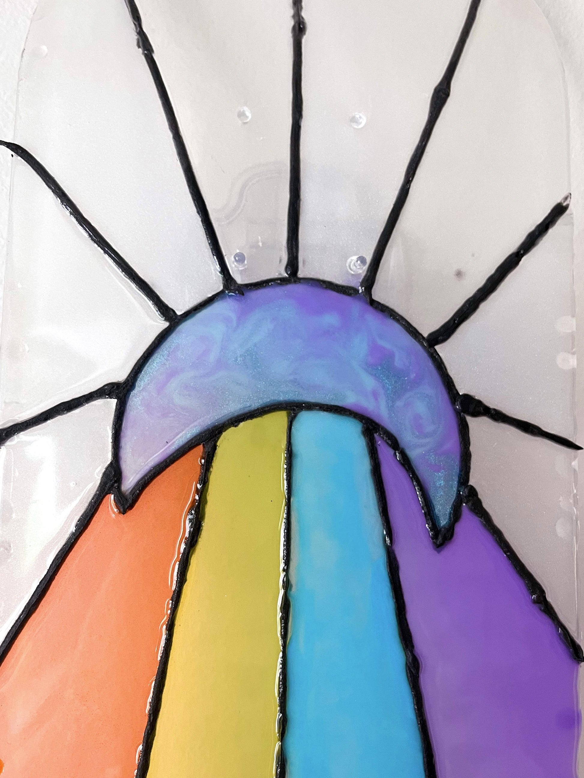 Close up of iridescent blue and purple resin moon on see-through stained glass skateboard deck wall art.