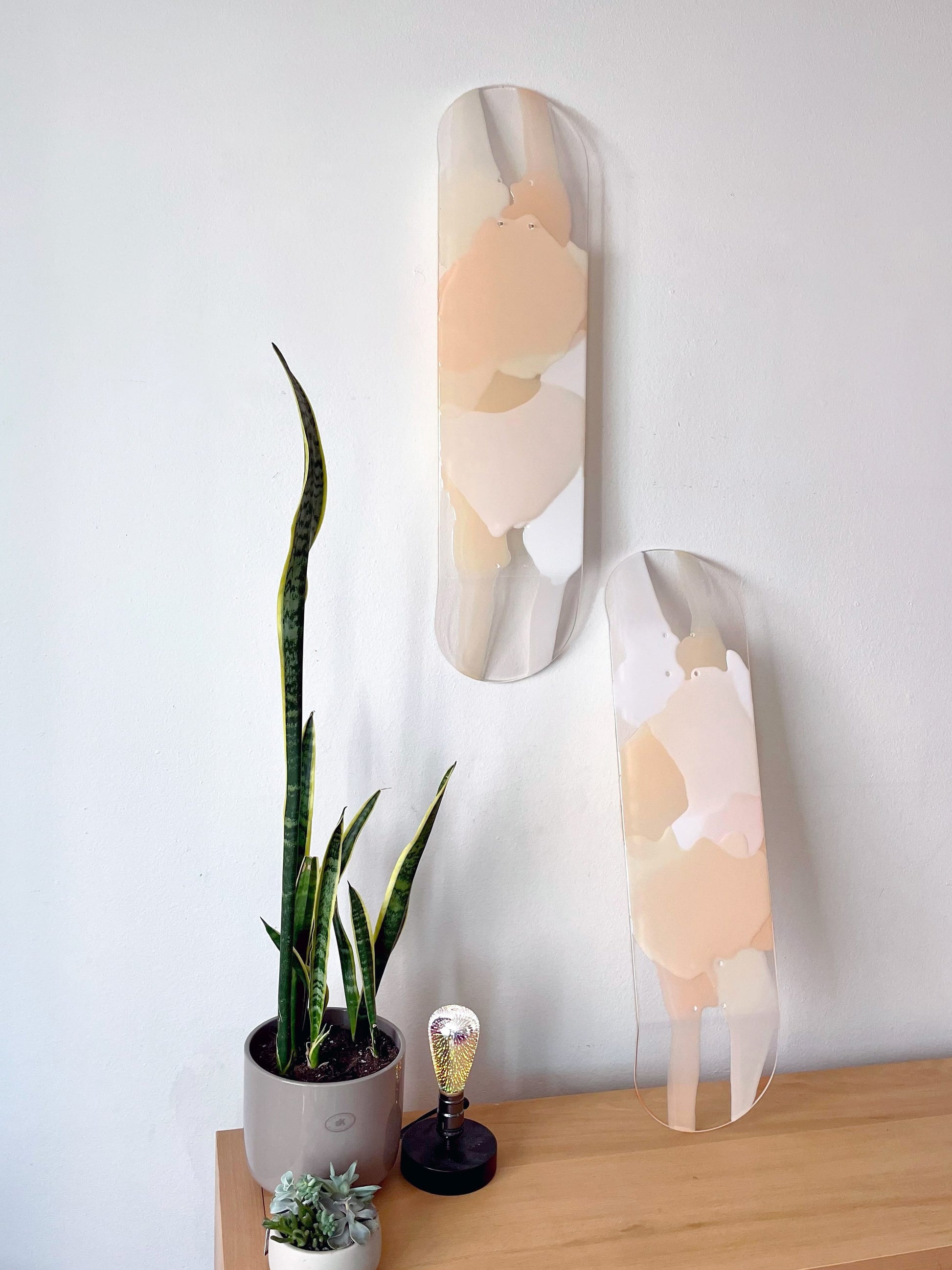 Two see-through, bohemian, neutral colored skateboard decks made of white, taupe, beige and cream resin layers.