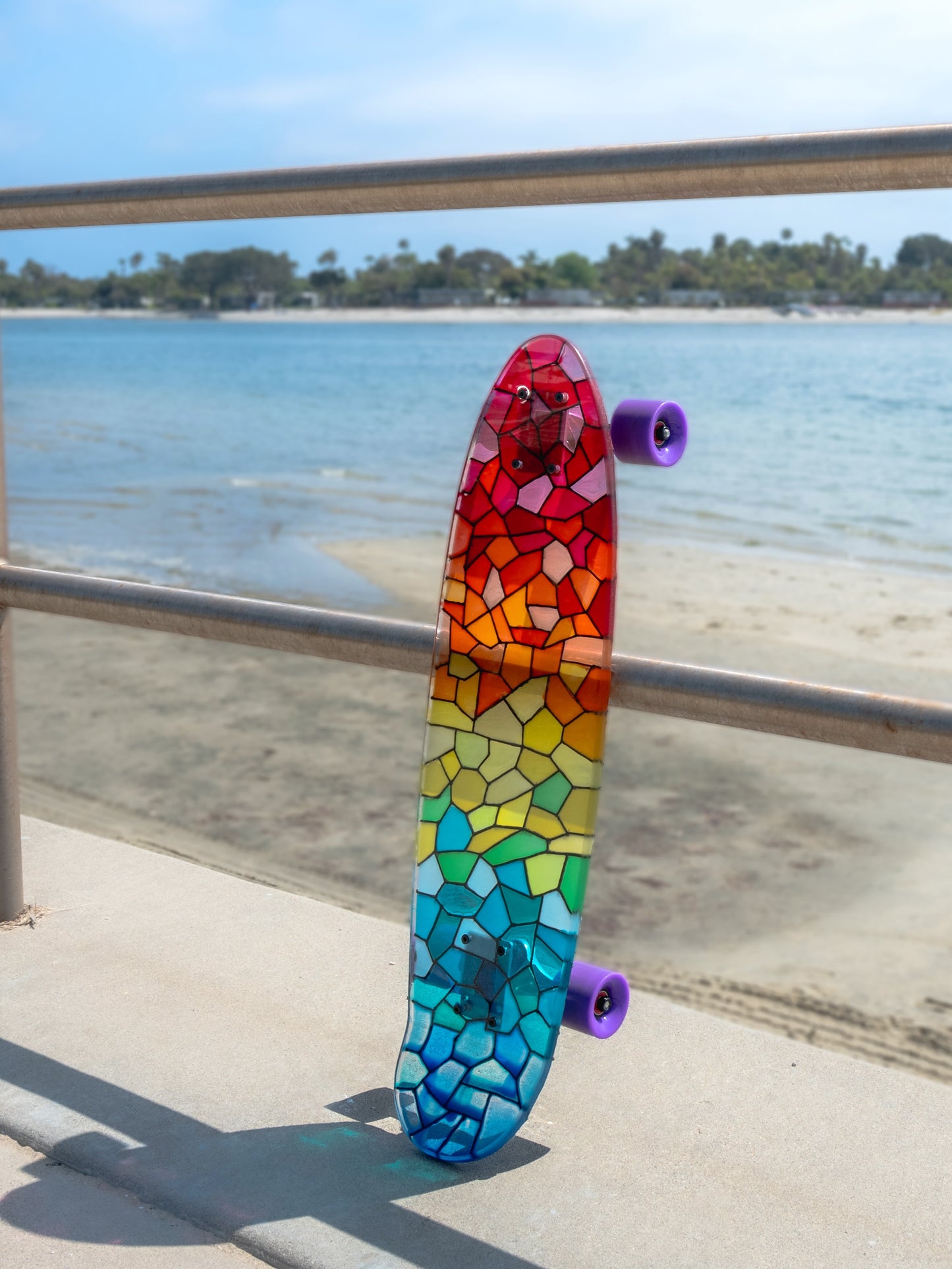 See-through rainbow stained glass skateboard with colorful shadow.