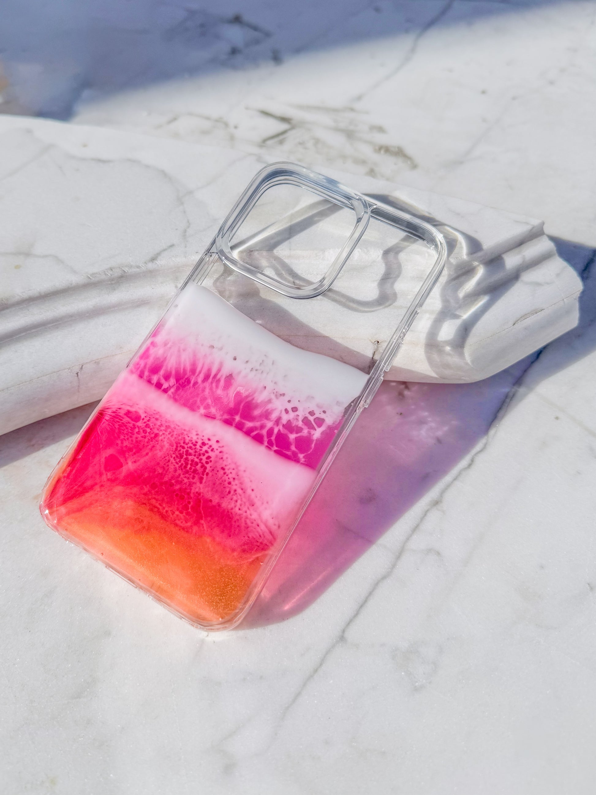 Pink, red and orange see-through resin ocean wave iPhone case.