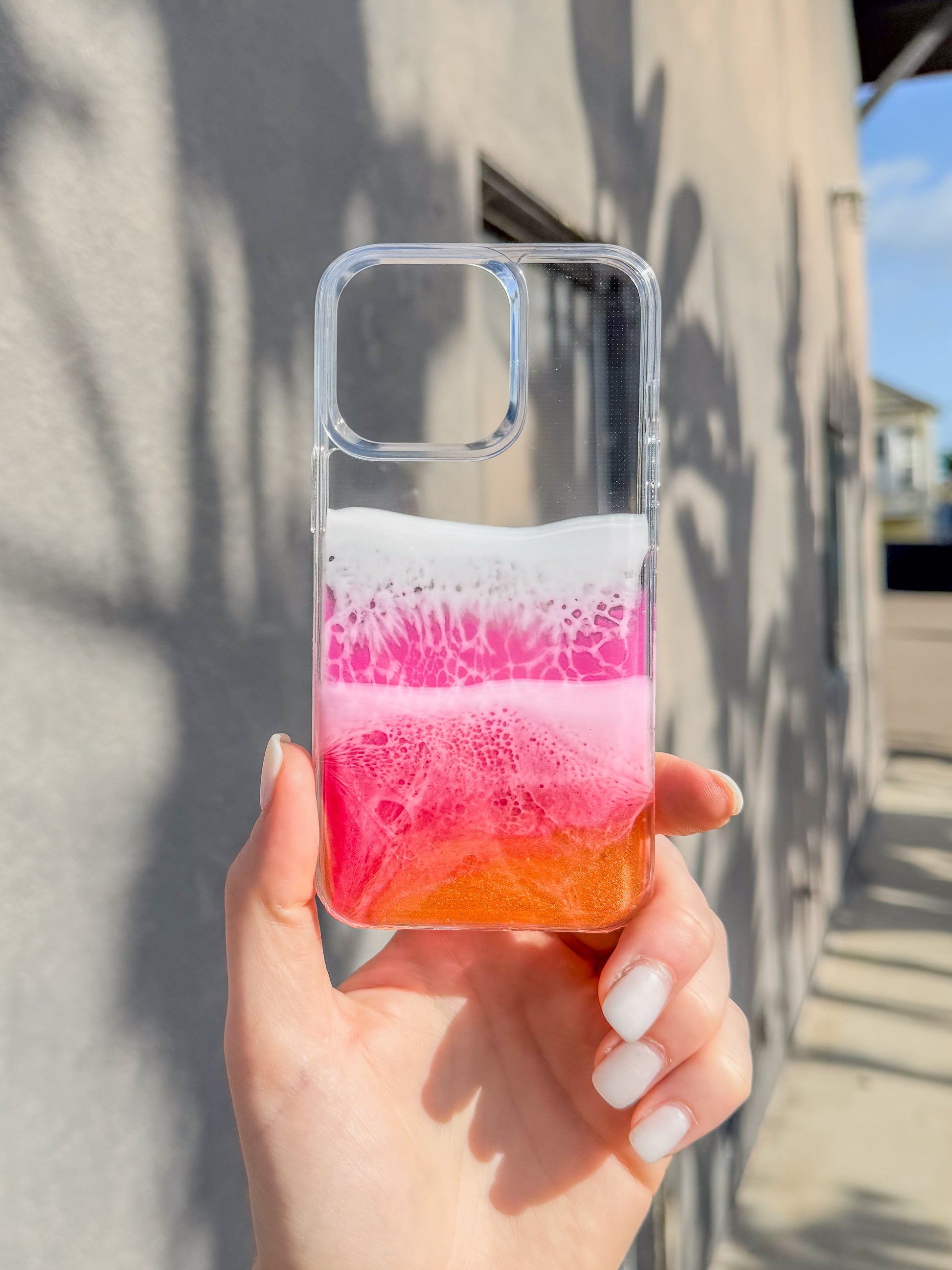 Pink, red and orange see-through resin ocean wave iPhone case.
