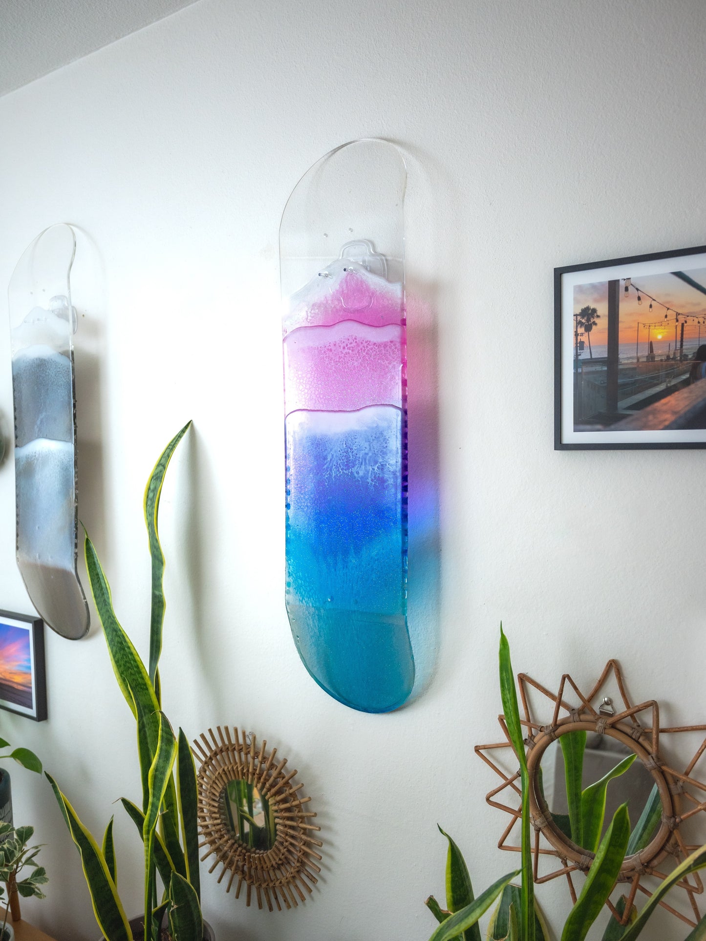 See through pink, purple, and blue ocean skateboard wall art with resin waves casting colorful shadow.