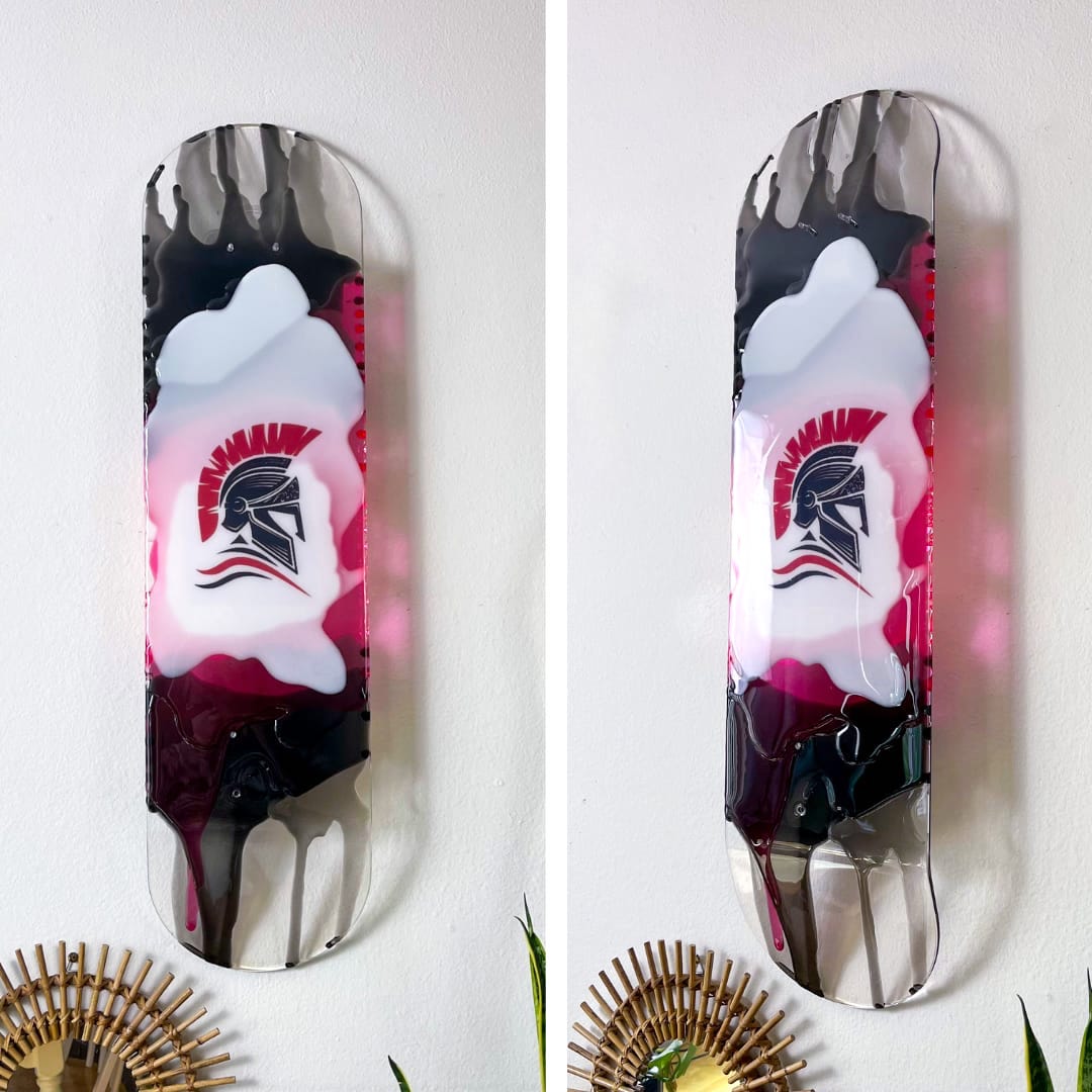 Custom see-through skateboard wall art with personalized logo casting colorful shadow on wall.