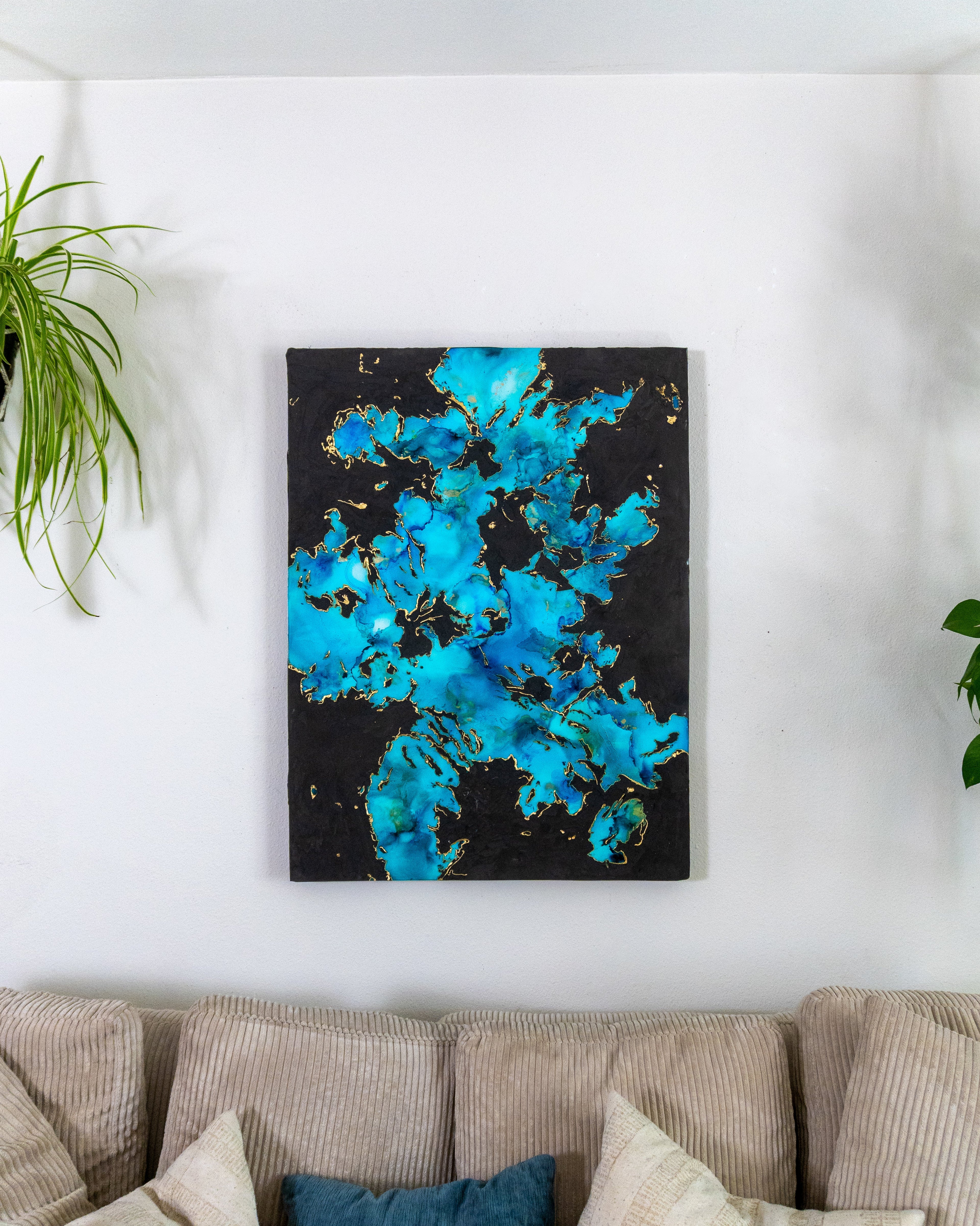 Abstract painting with blue and black colors on a wall above a beige sofa.