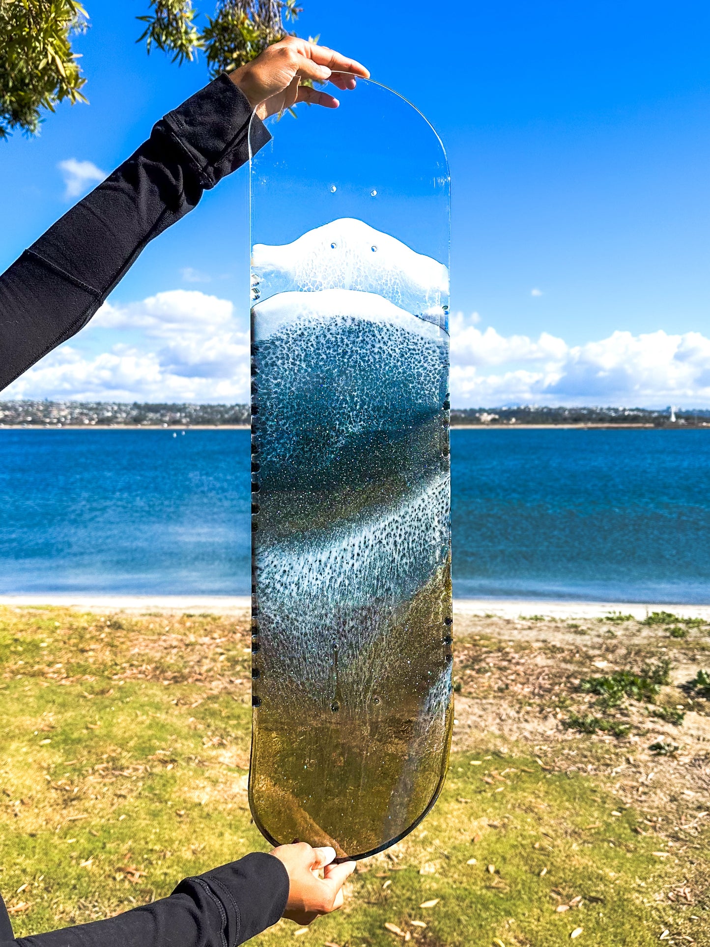 See through black and gold ocean skateboard wall art with iridescent sparkling resin waves.