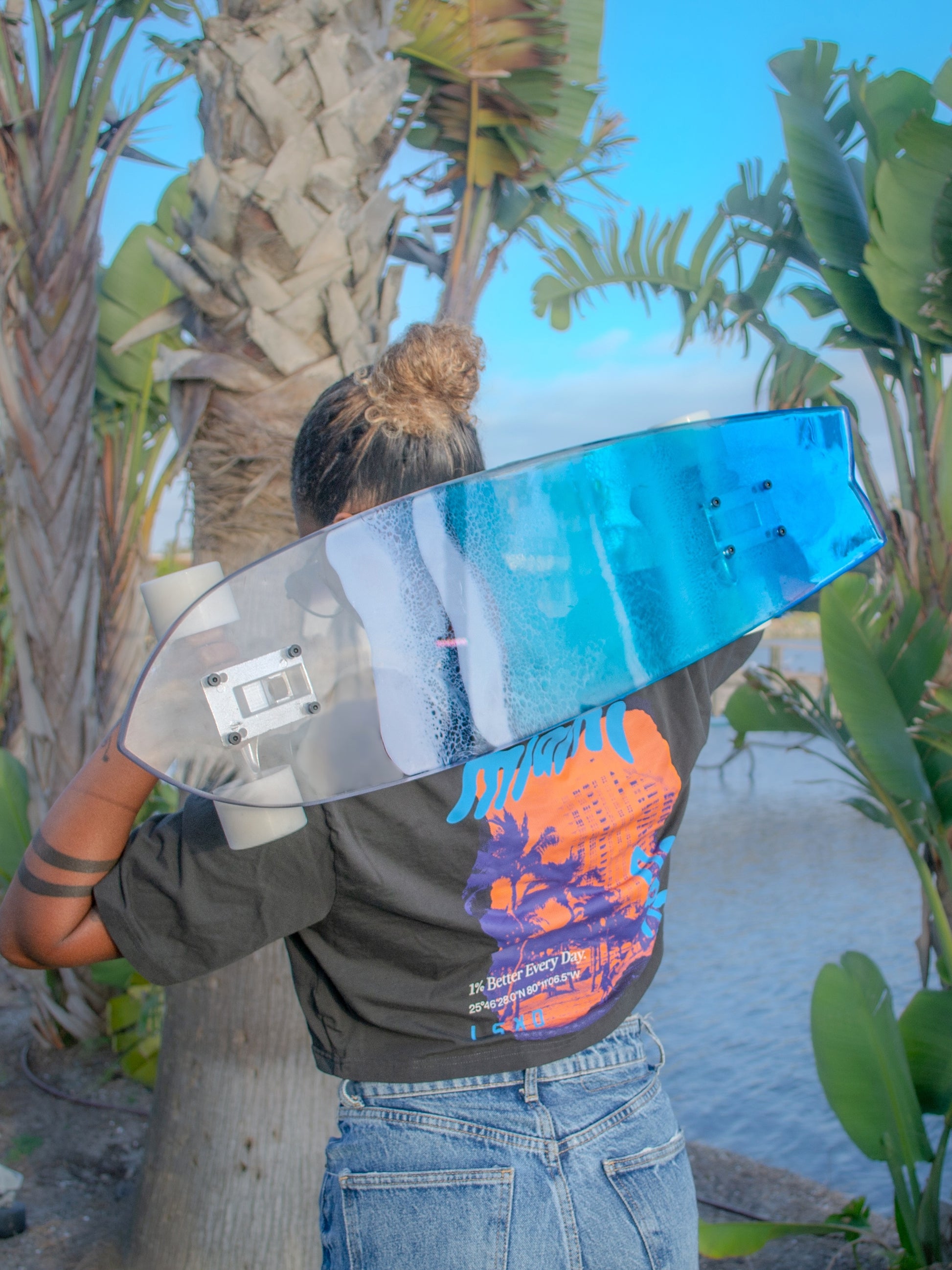 Blue, see-through resin ocean wave skateboard deck with fishtail casting colorful shadow.