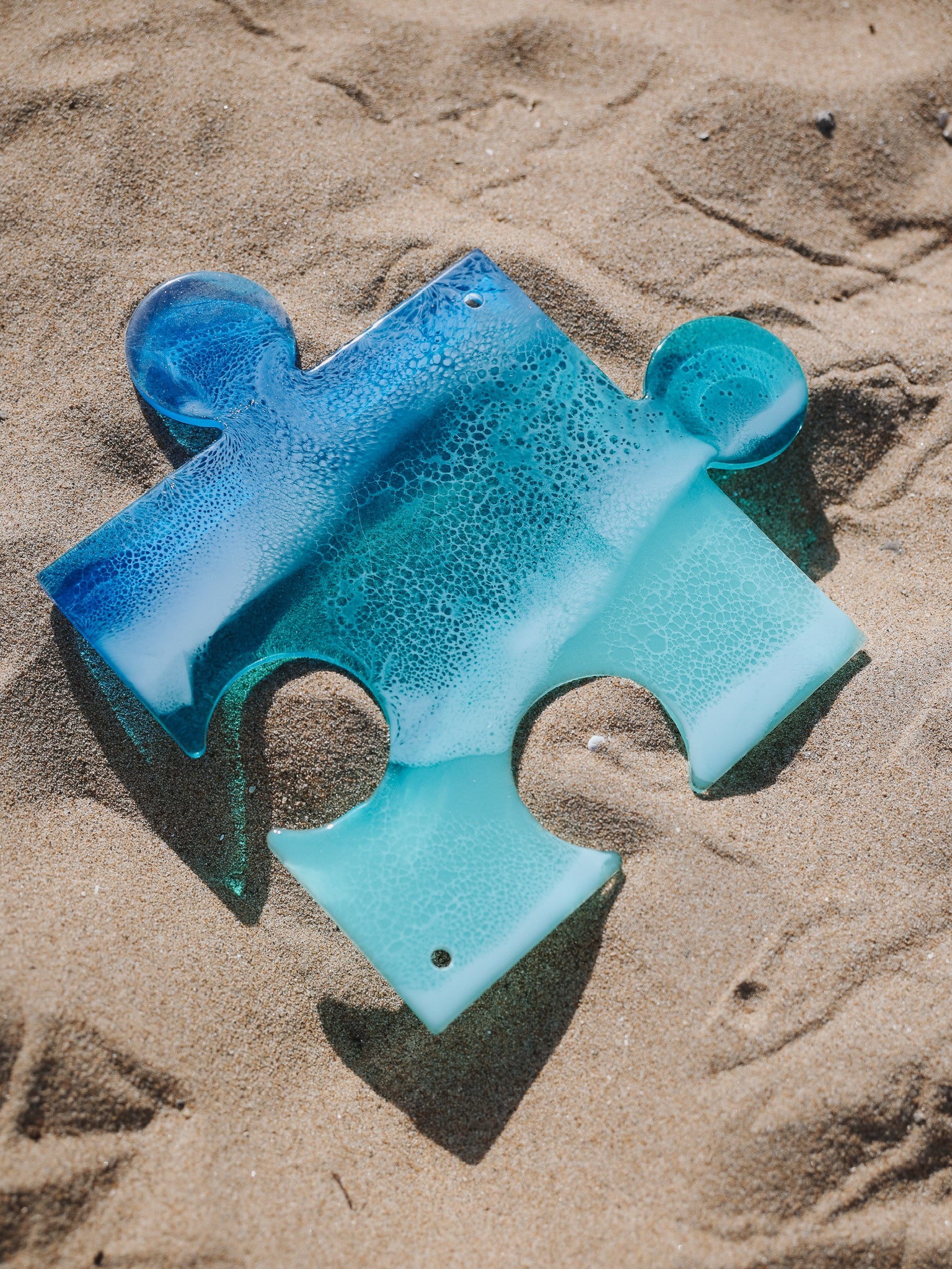 See-through, blue, stained glass ocean wave puzzle piece.
