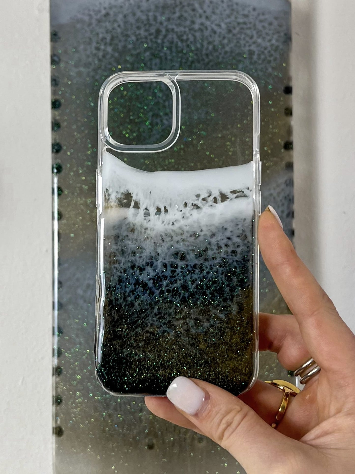 See-through black and gold sparkly ocean wave phone case.