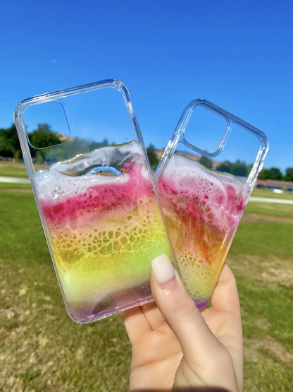 See-through rainbow resin ocean wave phone cases at park.
