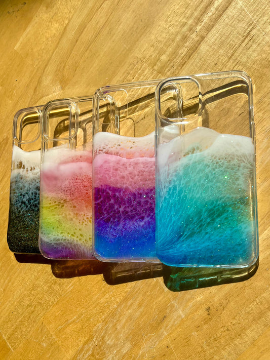 See-through ocean wave phone cases with colorful shadows on table. In black, rainbow, purple and blue colorways.