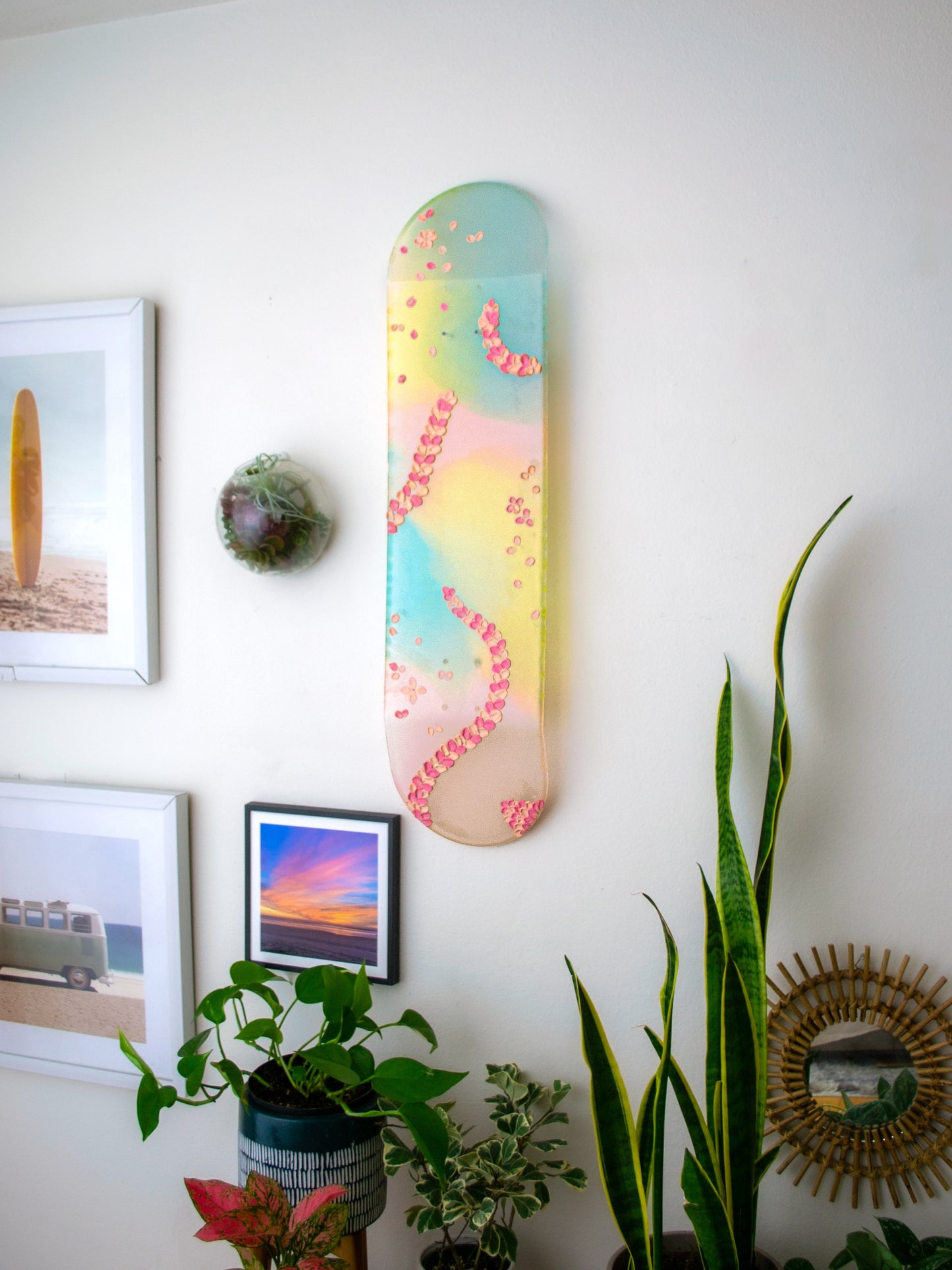 See-through pink, yellow, and blue shimmering resin skateboard wall art. Embellished with hand painted 3D pink flower petals.