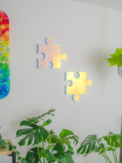 Unique, pink and yellow, see-through holographic resin puzzle piece wall art casting colorful, iridescent rainbow shadow.