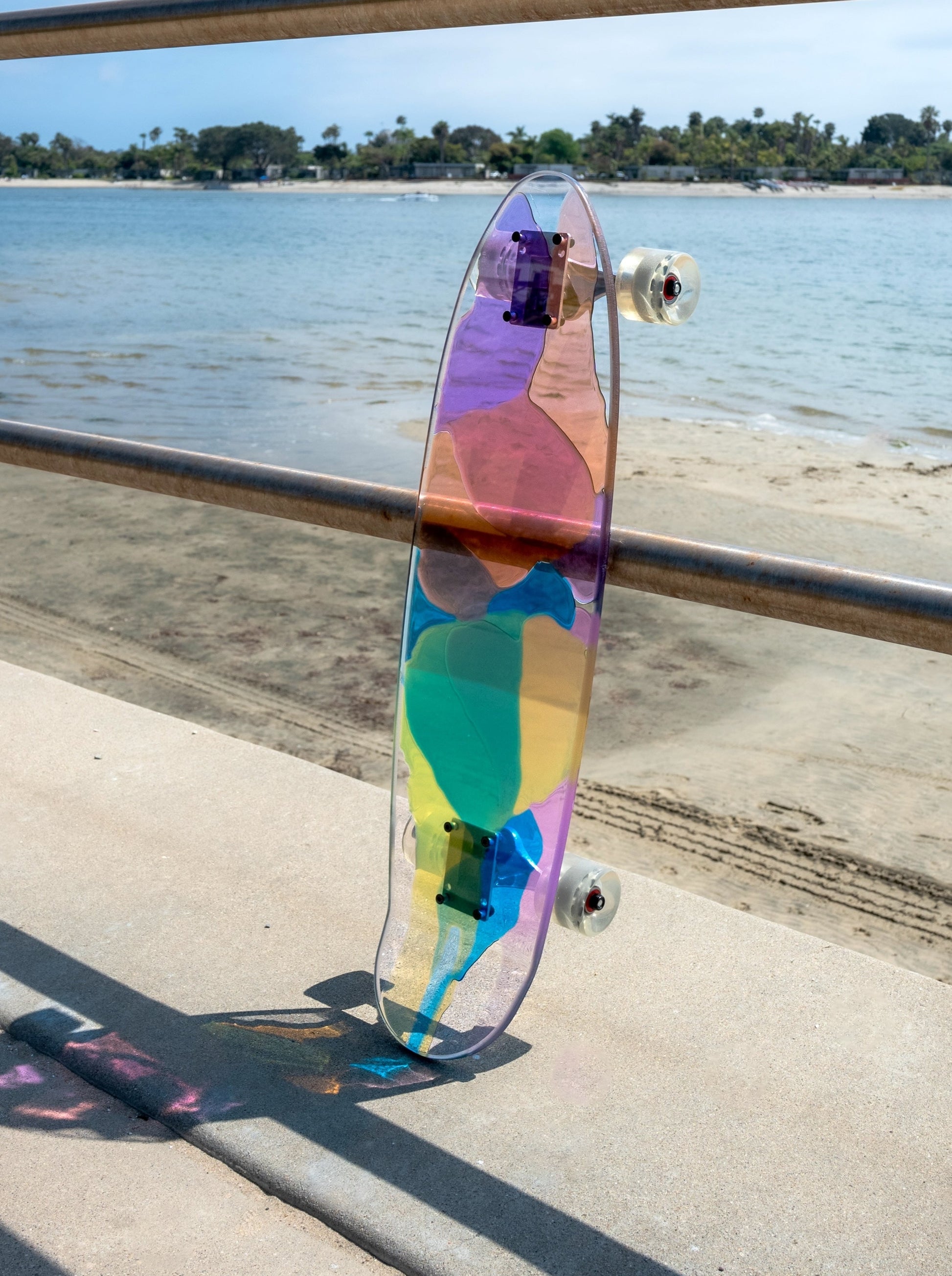 See-through rainbow stained glass skateboard with colorful shadow.