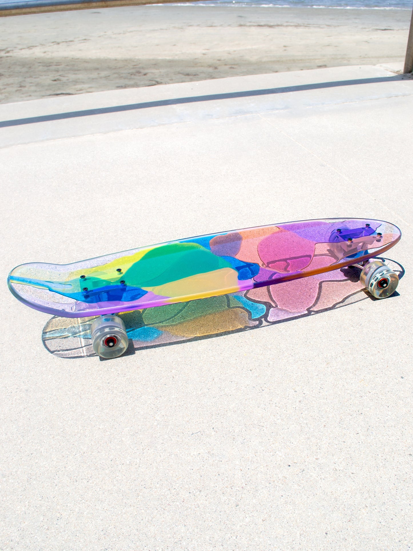 See-through rainbow stained glass skateboard with colorful shadow.