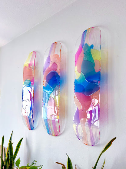 Colorful see-through stained glass skateboard decks with pink, purple, yellow, blue and orange resin casting vibrant shadow.