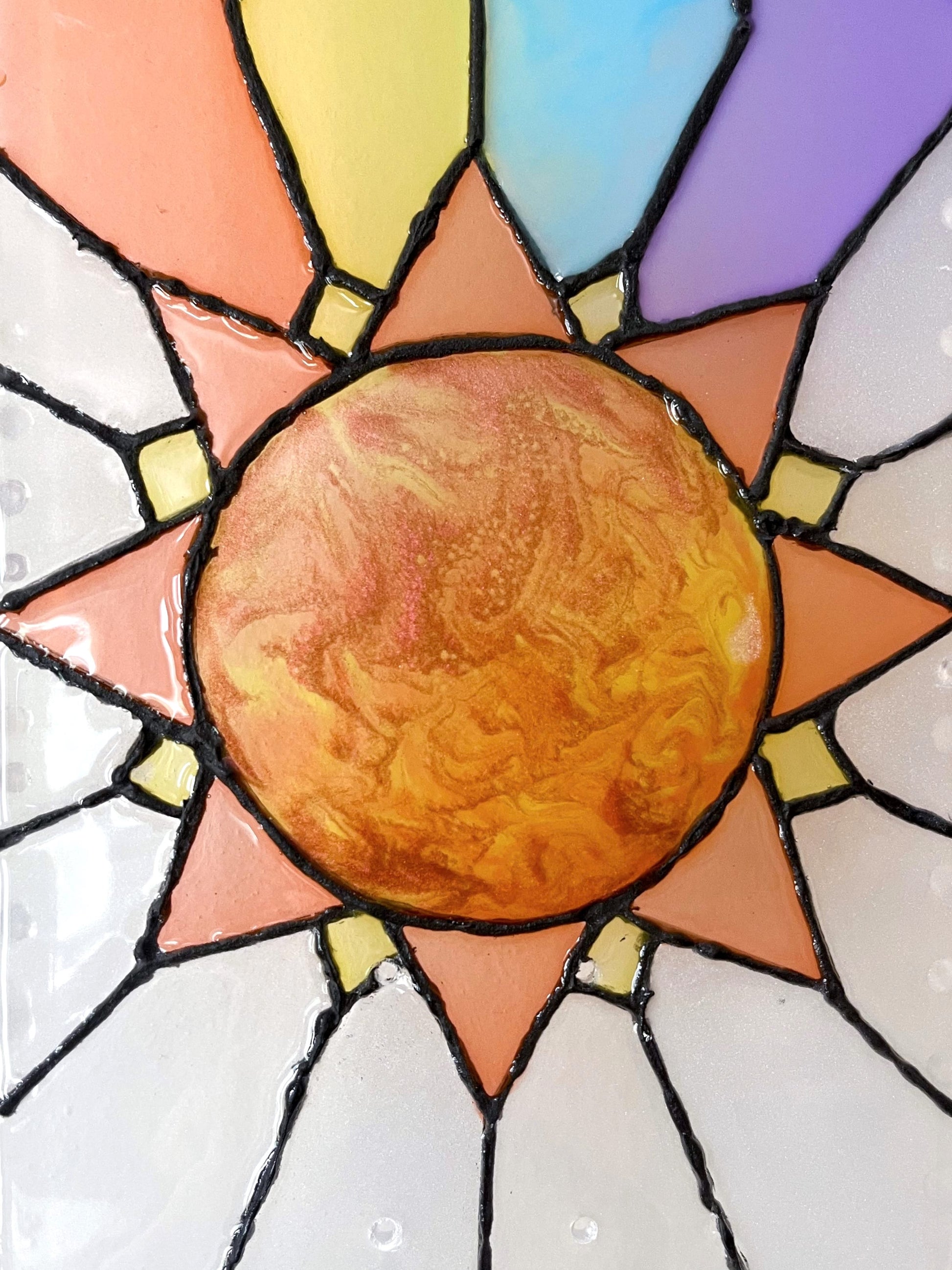 Close up of iridescent orange, yellow and red resin sun on see-through stained glass skateboard deck wall art.