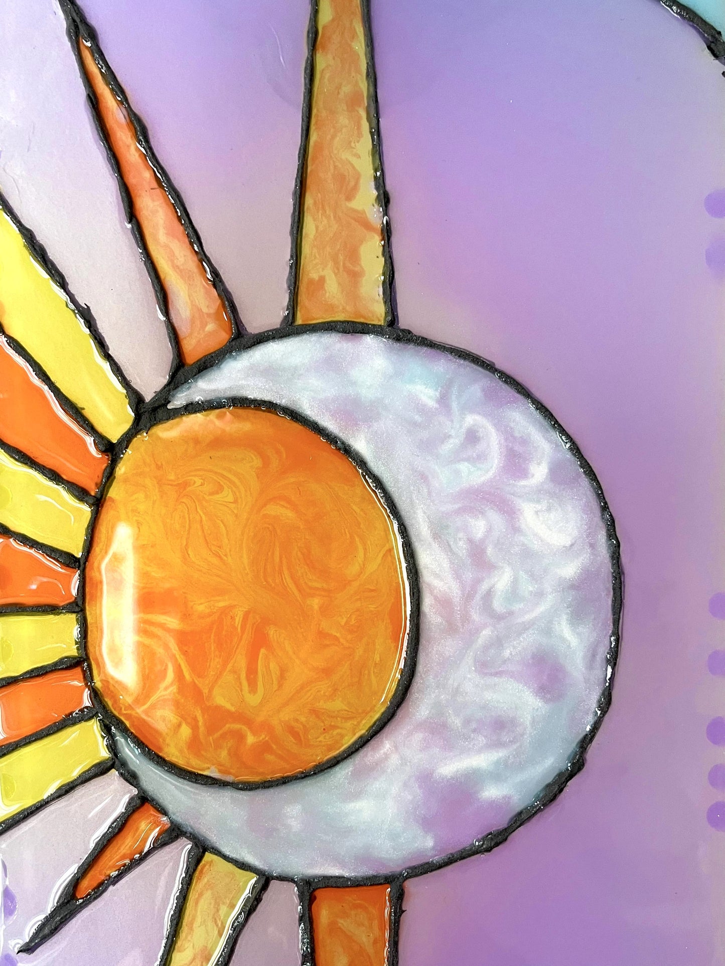 Close up of iridescent sun and moon design with swirling orange and yellow as well as purple, blue, and pearl resins.