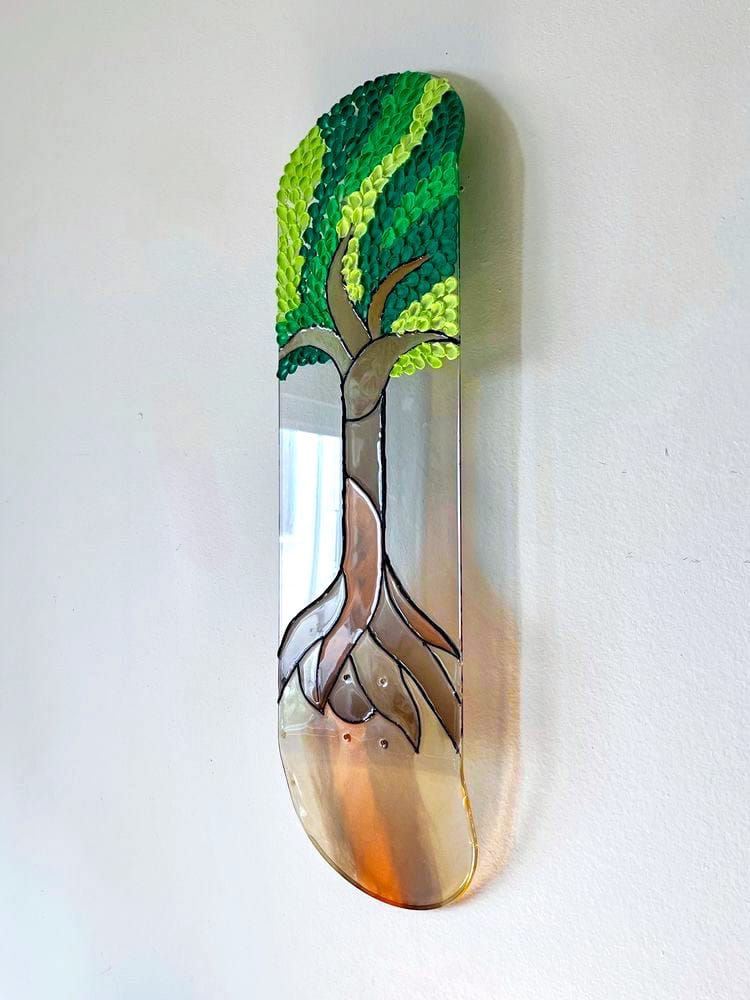 See-through stained glass 'Tree of Life' skateboard wall art with 3D leaves casting colorful shadow on wall.