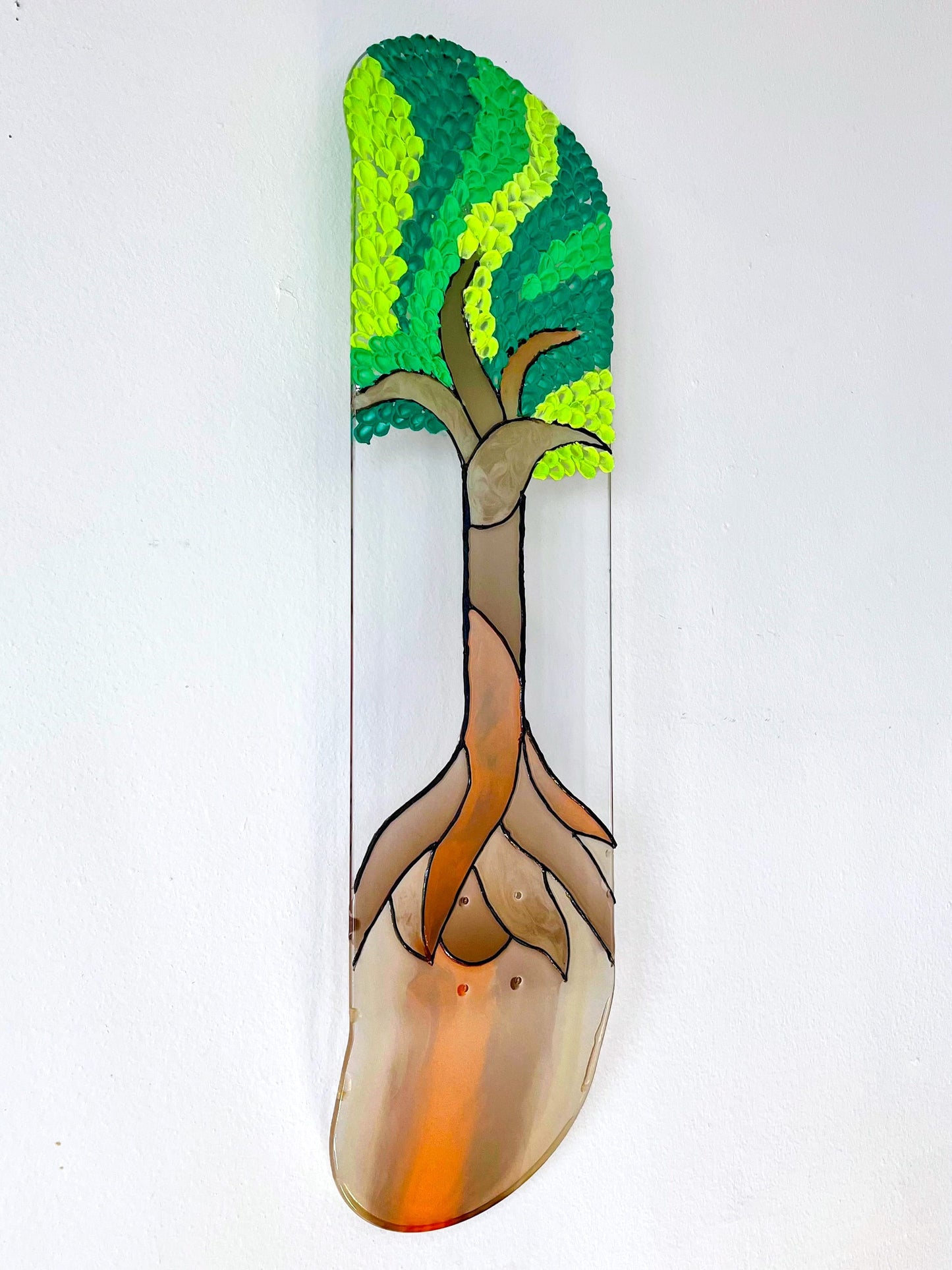 See-through stained glass 'Tree of Life' skateboard wall art with 3D leaves casting colorful shadow on wall.