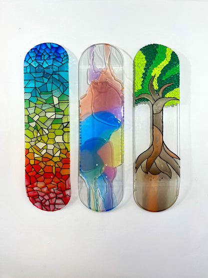 Three colorful, see-through resin skateboard decks hanging on wall.