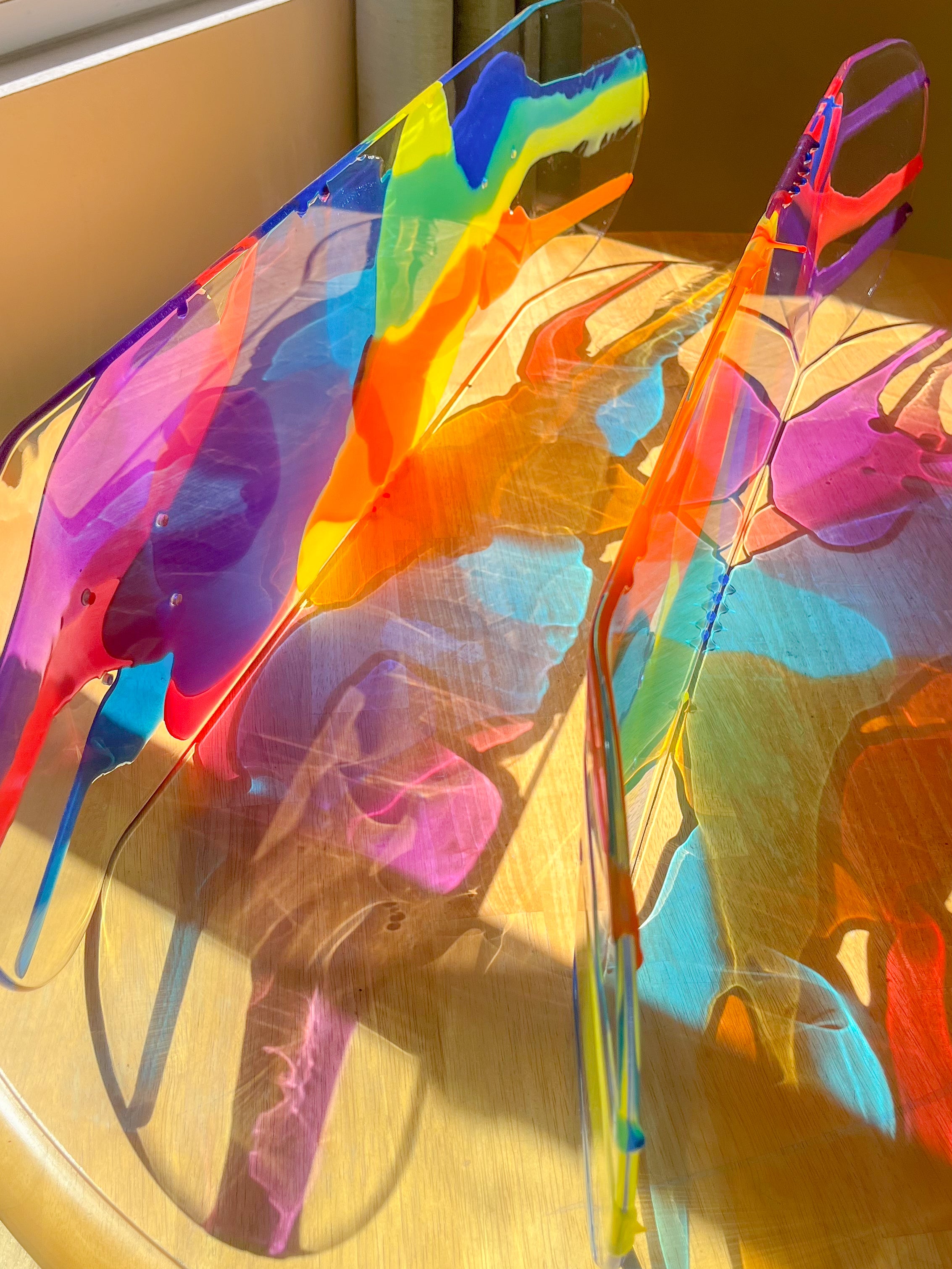 See-through, stained glass resin skateboard wall art with colorful rainbow shadow.