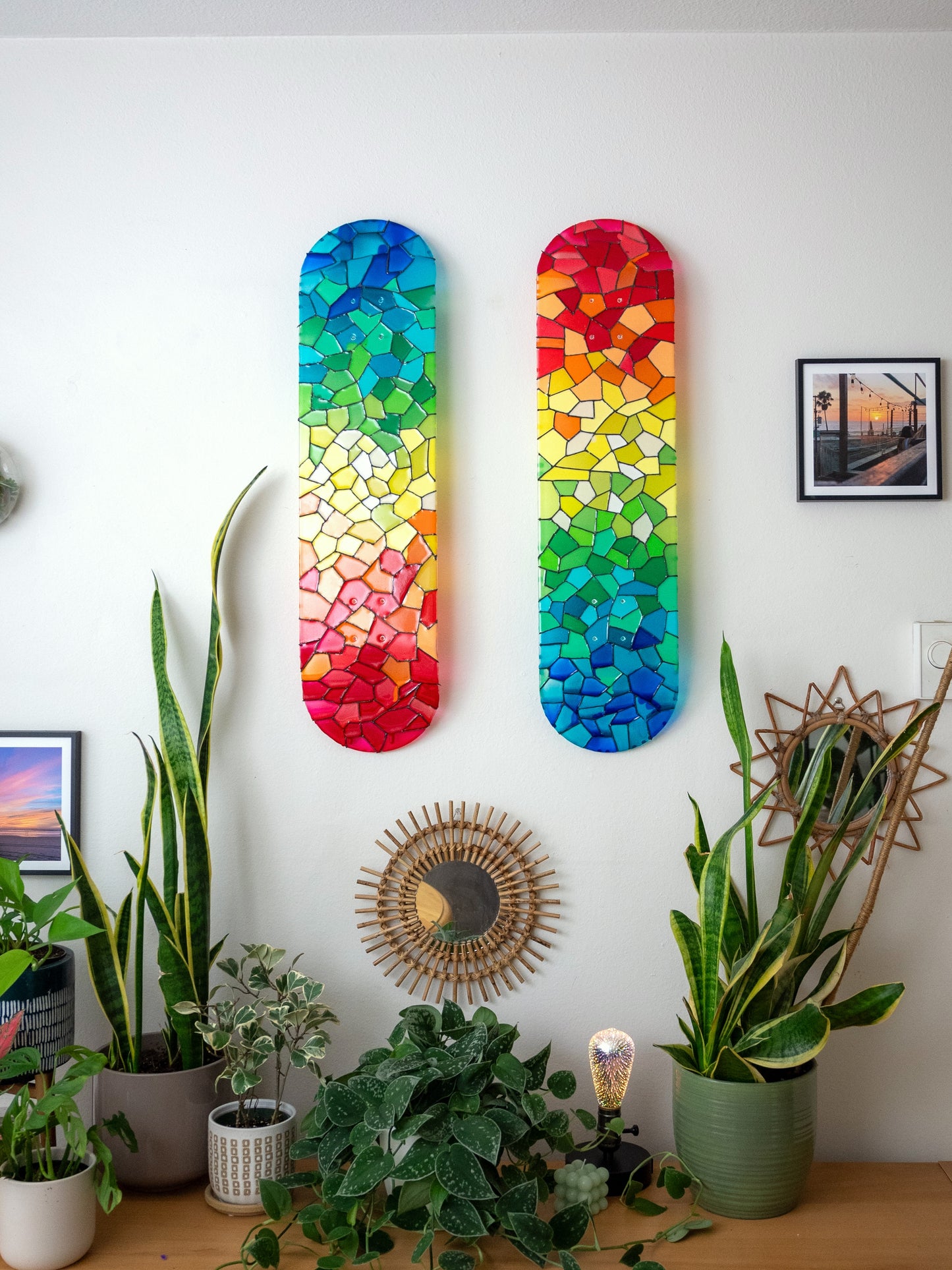 Two rainbow stained glass skateboard decks casting colorful shadows.