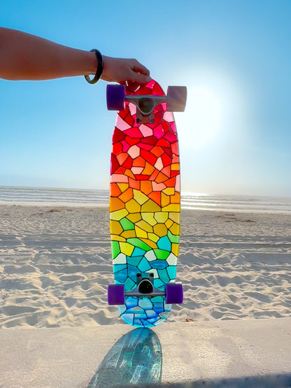 See-through rainbow stained glass skateboard with colorful shadow.